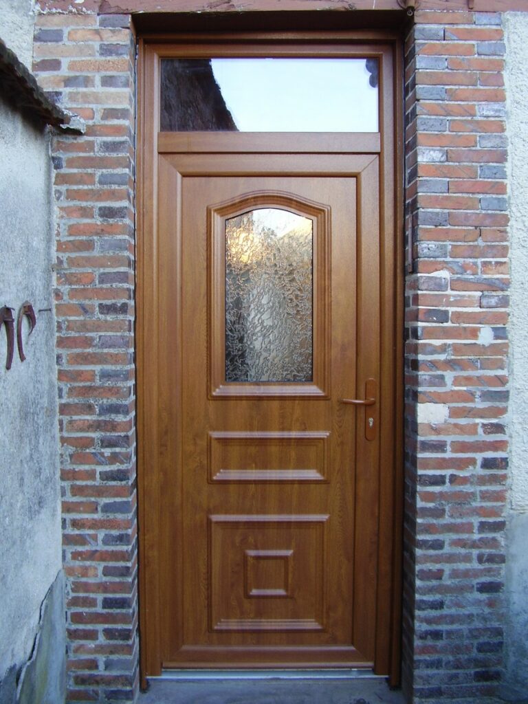 Porte d’entrée PVC modèle Dahlia, coloris chêne doré, avec imposte et vitrage Delta clair.