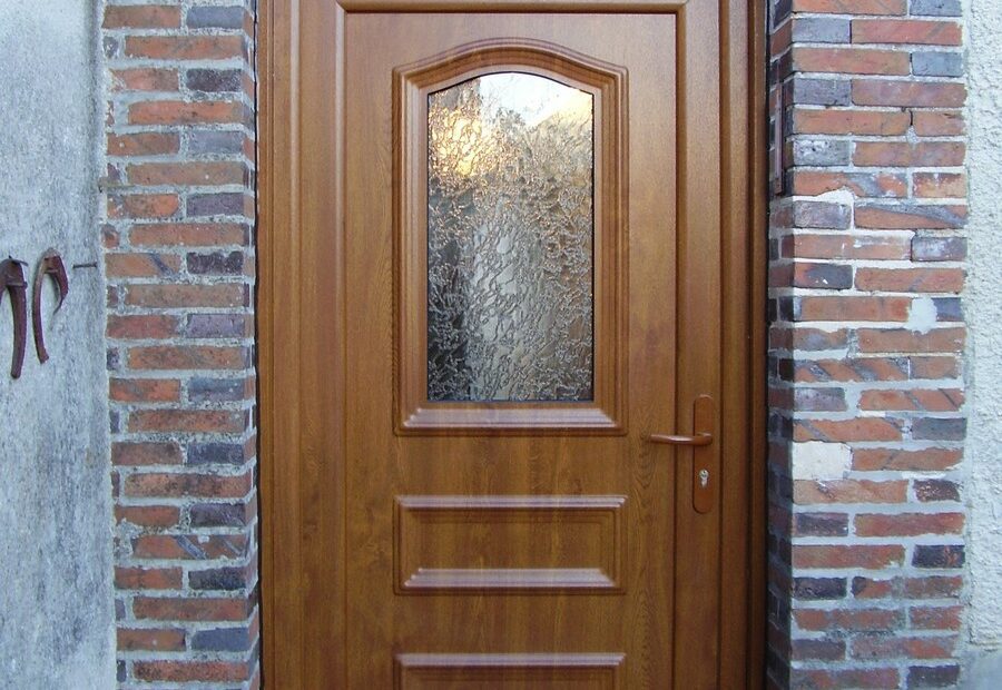 Porte d’entrée PVC modèle Dahlia, coloris chêne doré, avec imposte et vitrage Delta clair.