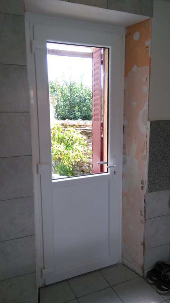 Vue intérieure de la porte d’entrée PVC blanche avec seuil aluminium.