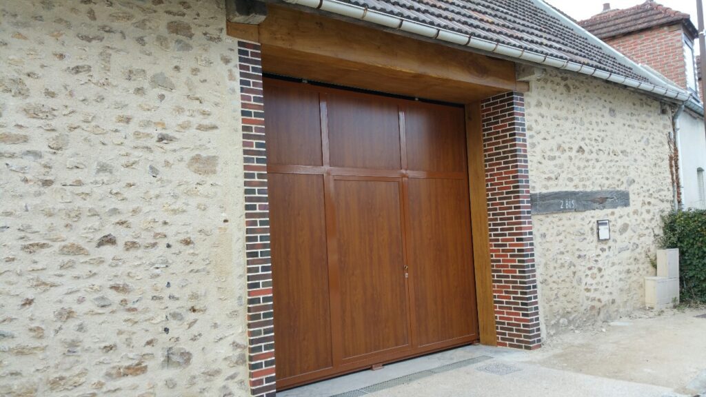 Porte de garage coulissante sur mesure avec portillon intégré, coloris chêne miel, ossature en tube à ailette.