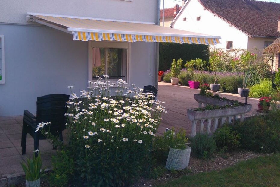 Store de terrasse existant rénové avec nouvelle toile acrylique rayée jaune et lambrequin vague, rentoilage sur mesure