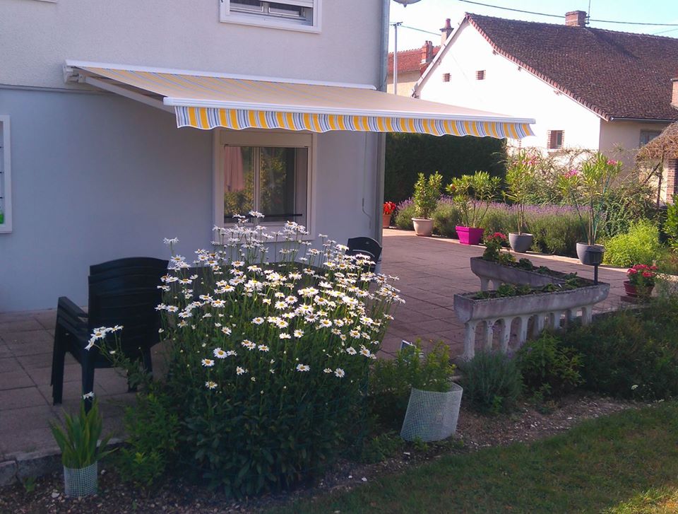 Store de terrasse existant rénové avec nouvelle toile acrylique rayée jaune et lambrequin vague, rentoilage sur mesure