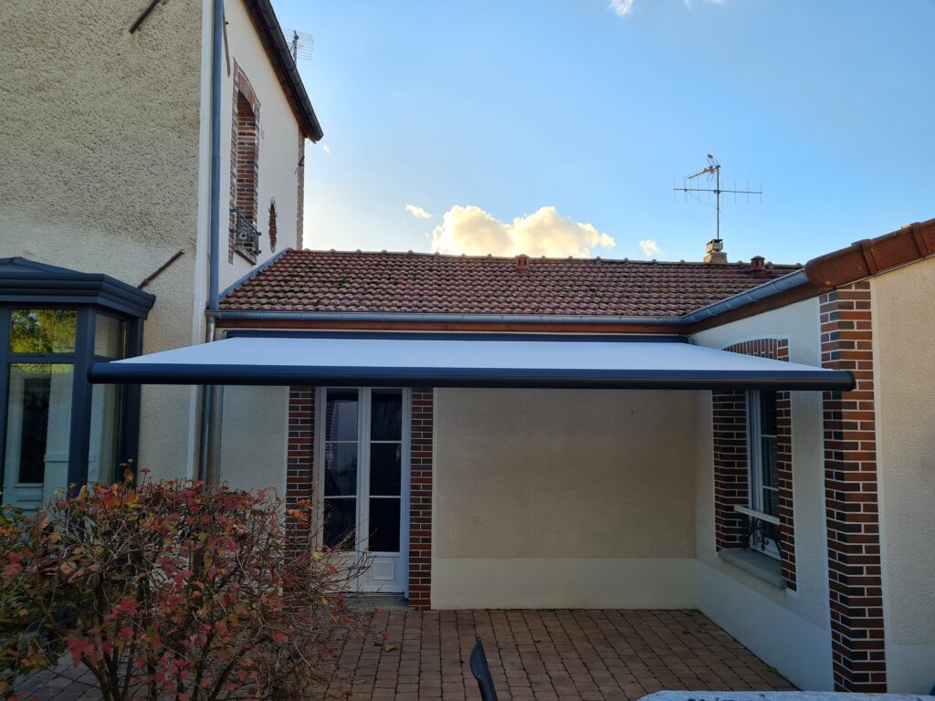 Store Félicia ouvert – armature gris anthracite, toile blanche déployée.