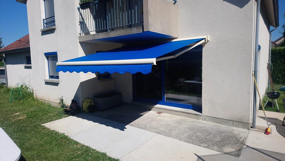 Store banne Fétuna ouvert sur terrasse, armature aluminium blanc et toile acrylique bleu unie avec lambrequin “vague”, pose sur mesure
