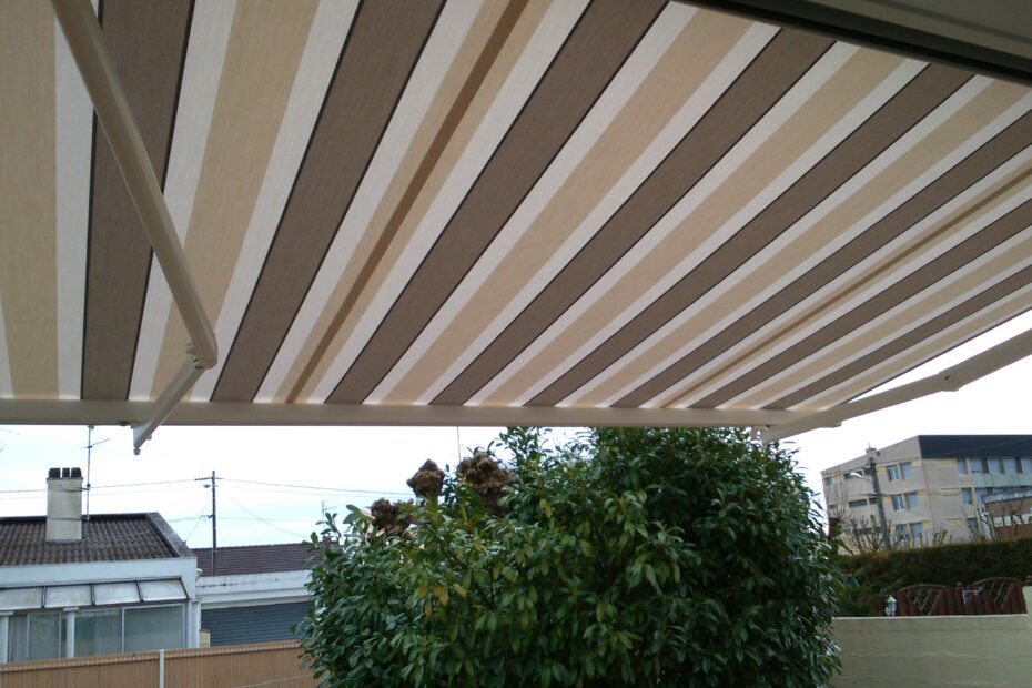 Store banne Horizon ouvert, vue en angle de la terrasse, installation professionnelle et toile beige rayée