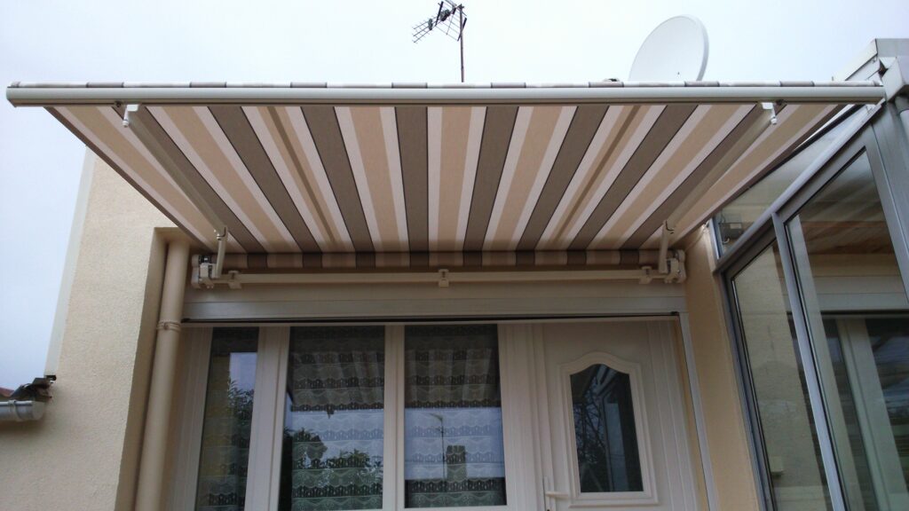 Détail du store Horizon ouvert avec toile acrylique beige rayée et armature aluminium blanc RAL9010