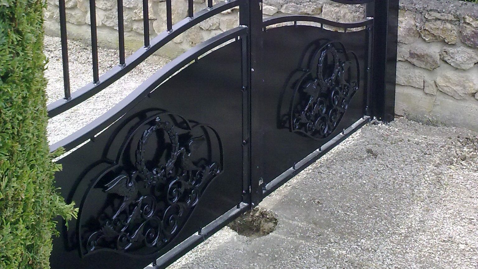 Détail des motifs volutes et oiseaux sur portail acier chapeau de gendarme