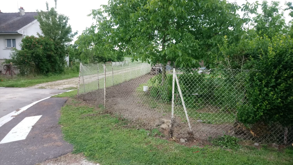 Vue de la clôture existante avant rénovation avec panneaux occultants