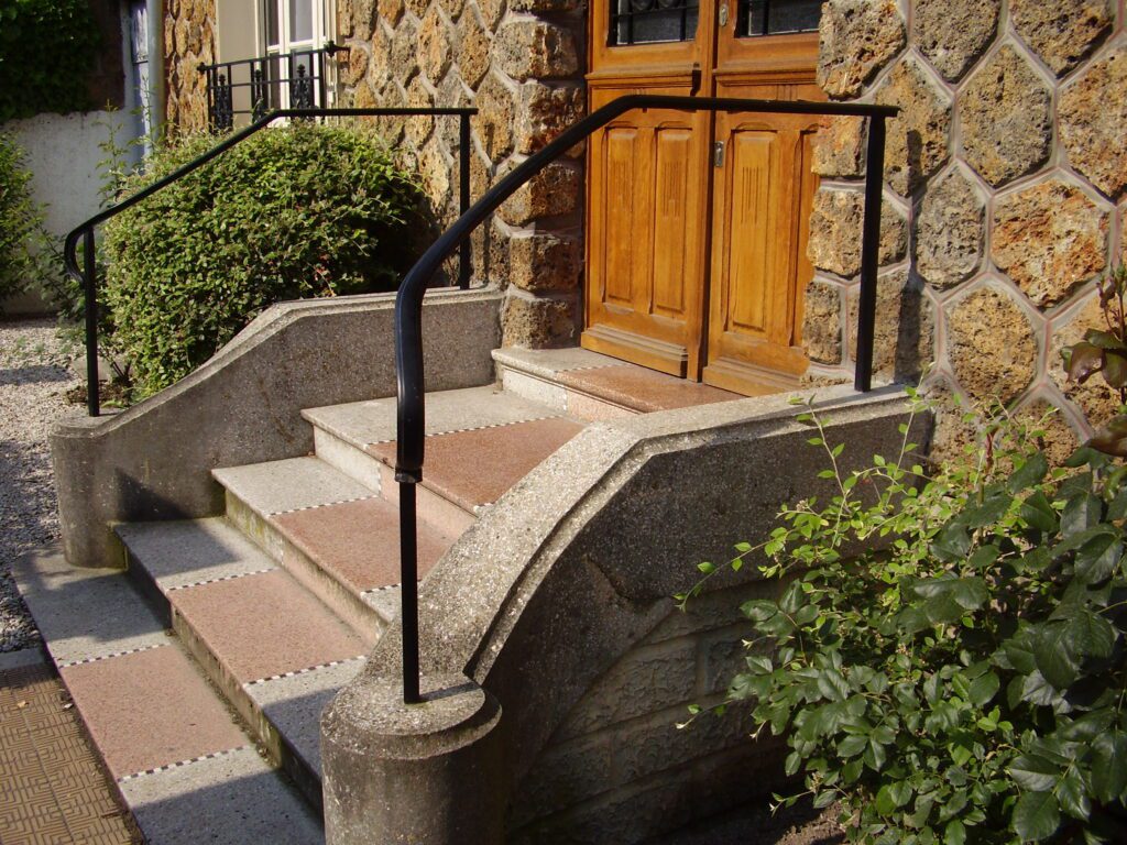 Garde-corps métallique avec main courante moulurée cintrée suivant la pente de l’escalier, finition noire