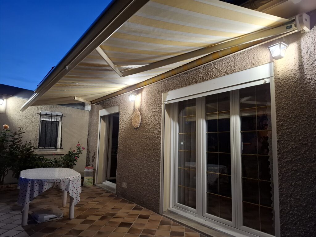 Store banne Franciaflex Félicia ouvert avec toile rayée jaune sur terrasse