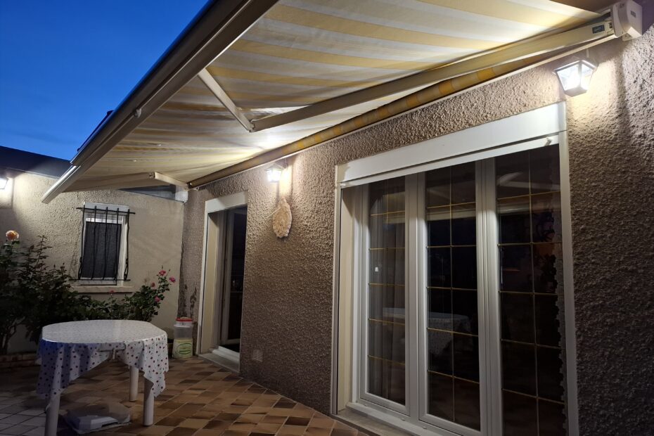 Store banne Franciaflex Félicia ouvert avec toile rayée jaune sur terrasse