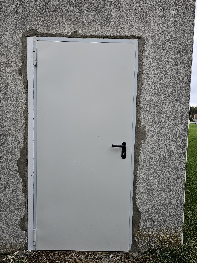 Porte de chaufferie blanche posée avec reprise de maçonnerie extérieure