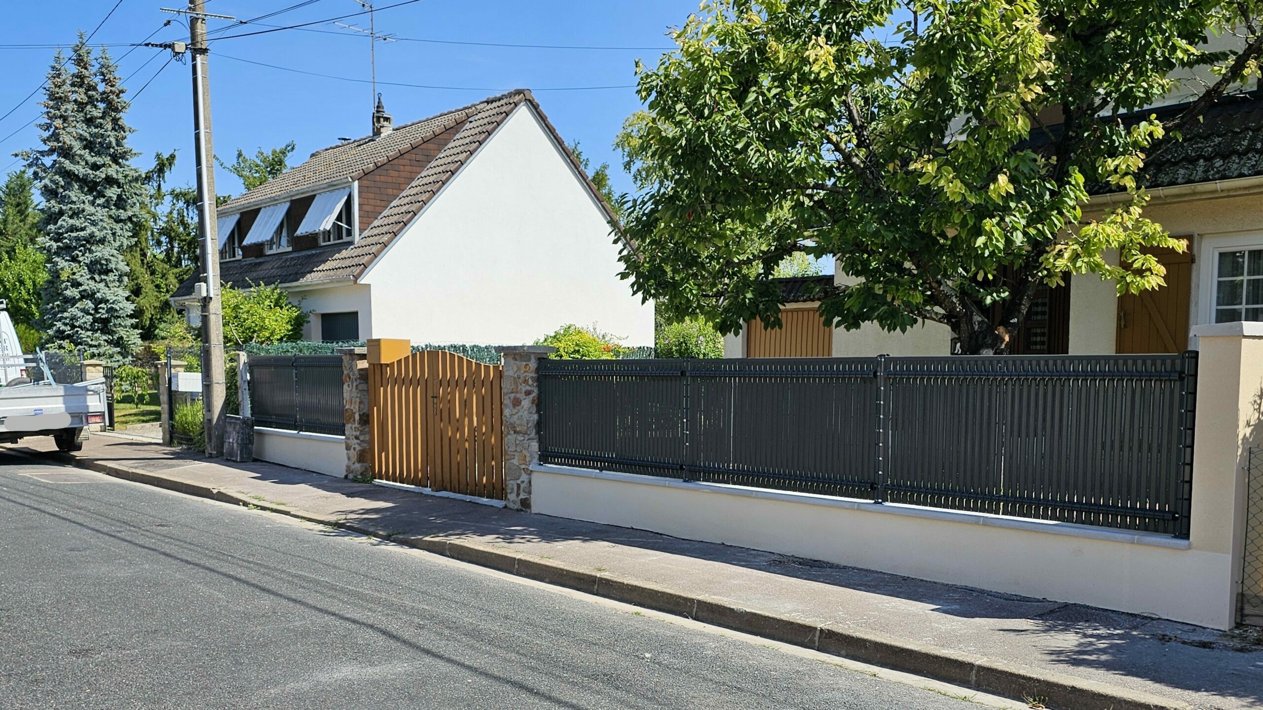 Clôture rigide avec panneaux occultants gris RAL 7016 installée sur un muret existant.